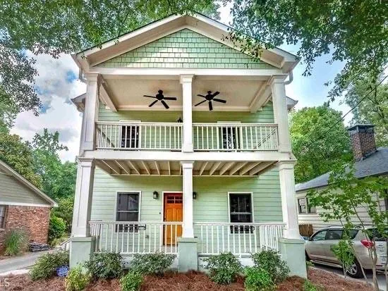 Classic two-story home featuring a welcoming front façade with white columns and railing details