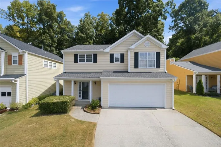 Two-story residence featuring light-colored siding, a two-car garage, and a covered front entry with columns