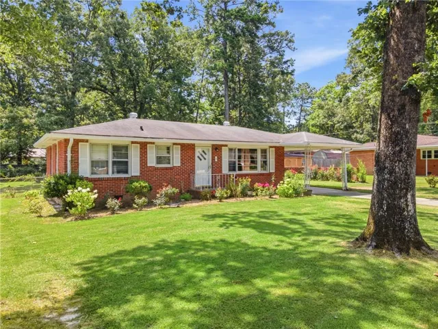 Brick ranch-style residence featuring a covered front entry, white window shutters, and a carport