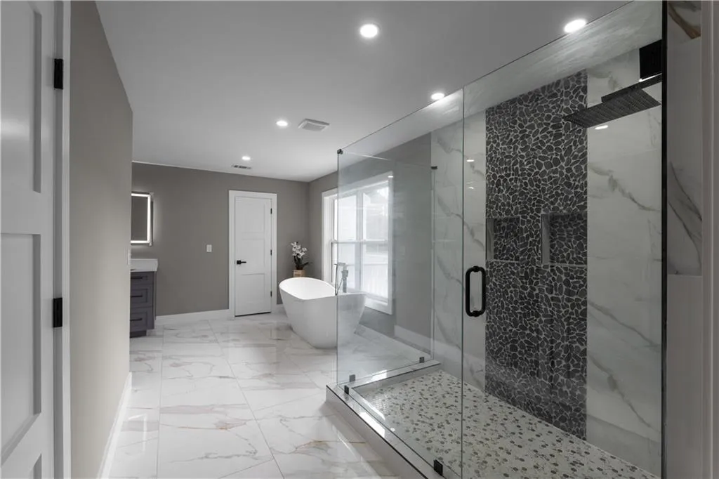Full bathroom featuring a freestanding tub, vanity, a marble finish shower, light marble finish flooring, and recessed lighting