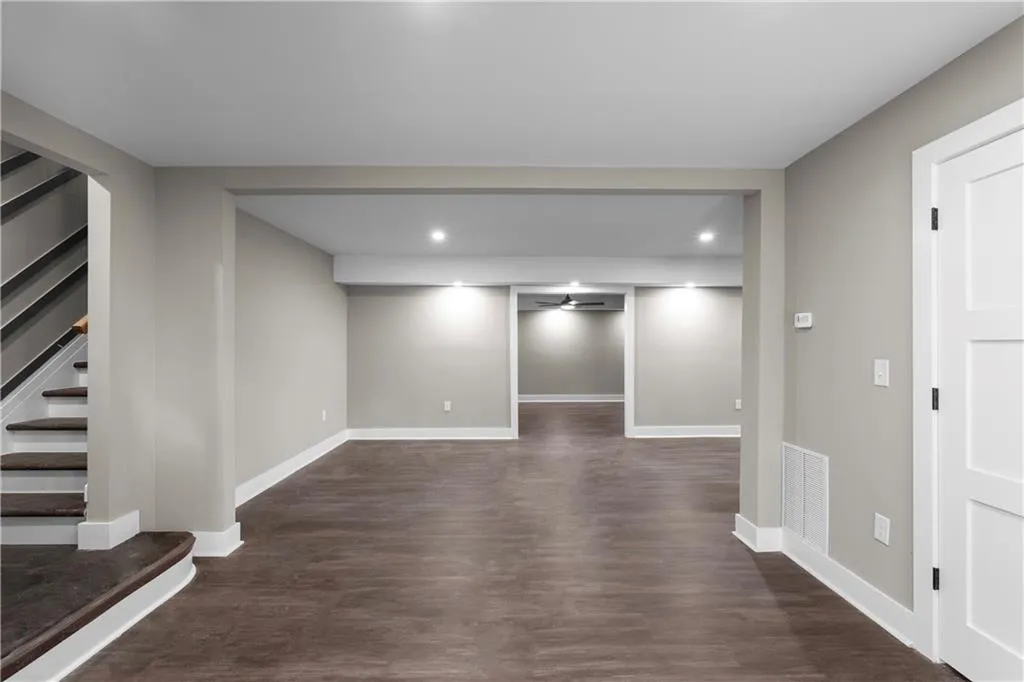 Basement featuring dark wood-style flooring, stairs, recessed lighting, and a ceiling fan