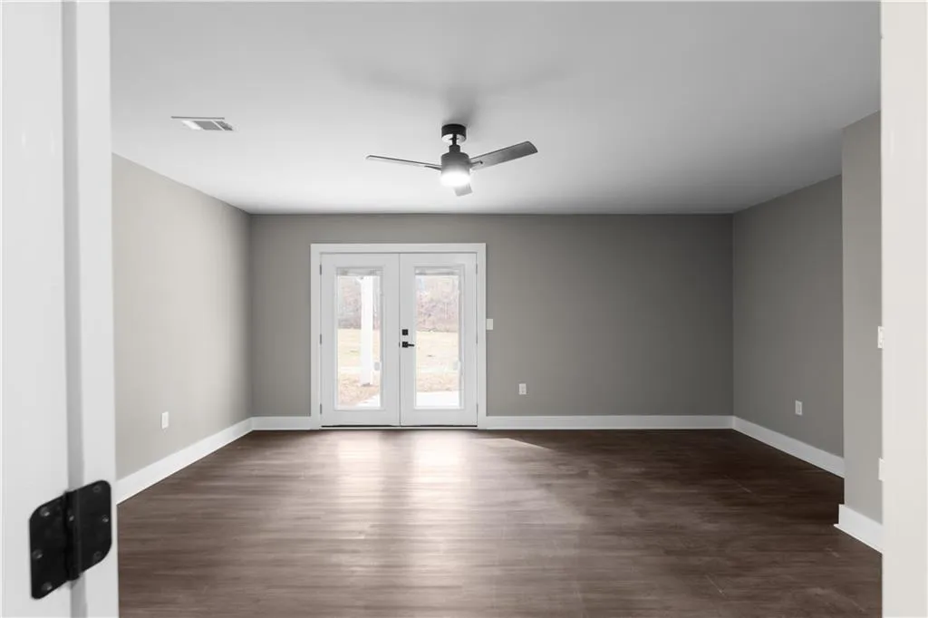 Spare room featuring dark wood-style flooring, french doors, and ceiling fan