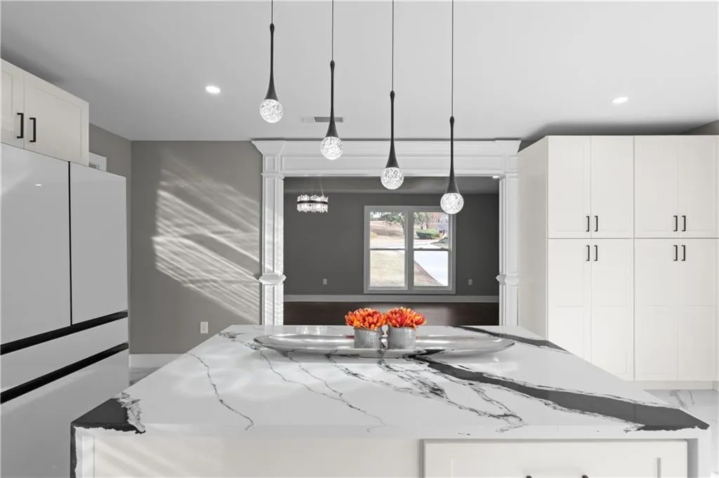 Kitchen with white cabinetry, light stone countertops, pendant lighting, a kitchen island, and recessed lighting