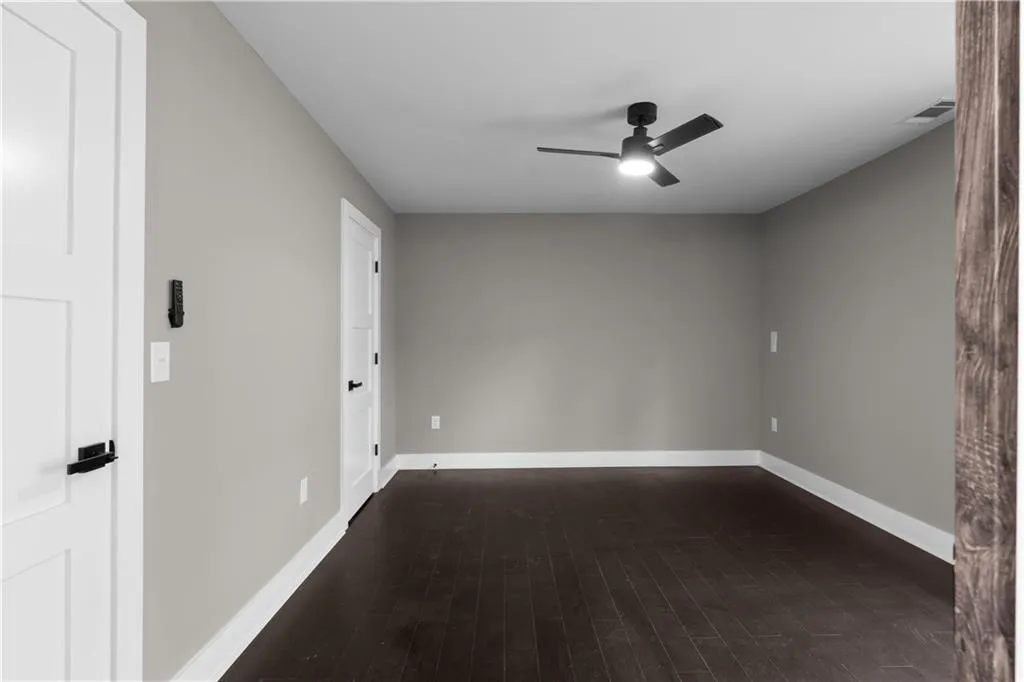 Empty room featuring dark wood-style floors and a ceiling fan