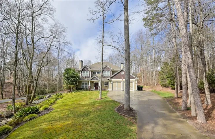 Traditional-style residence featuring a prominent front entrance, dual garage doors, and a stone chimney