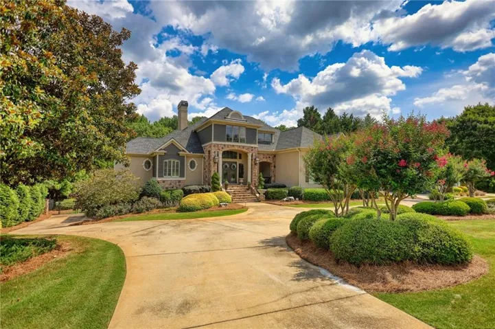 Grand stucco and stone-accented residence featuring a prominent entryway with arched detailing
