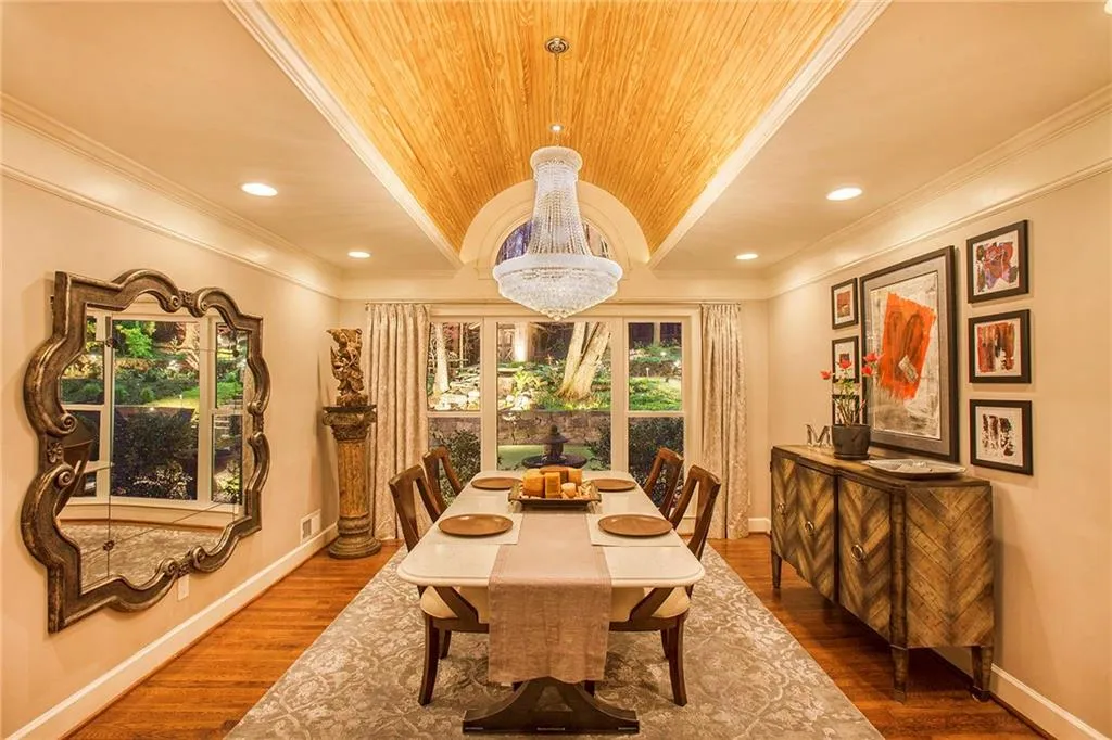 Evening shot of Dining room with wood barrel ceiling and shimmering chandelier with views to outside.