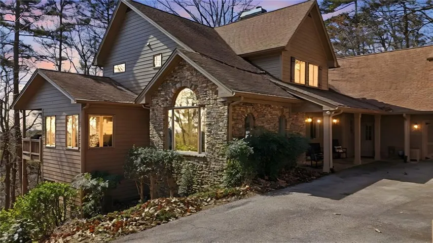 View of property exterior with stone siding, driveway, and a chimney