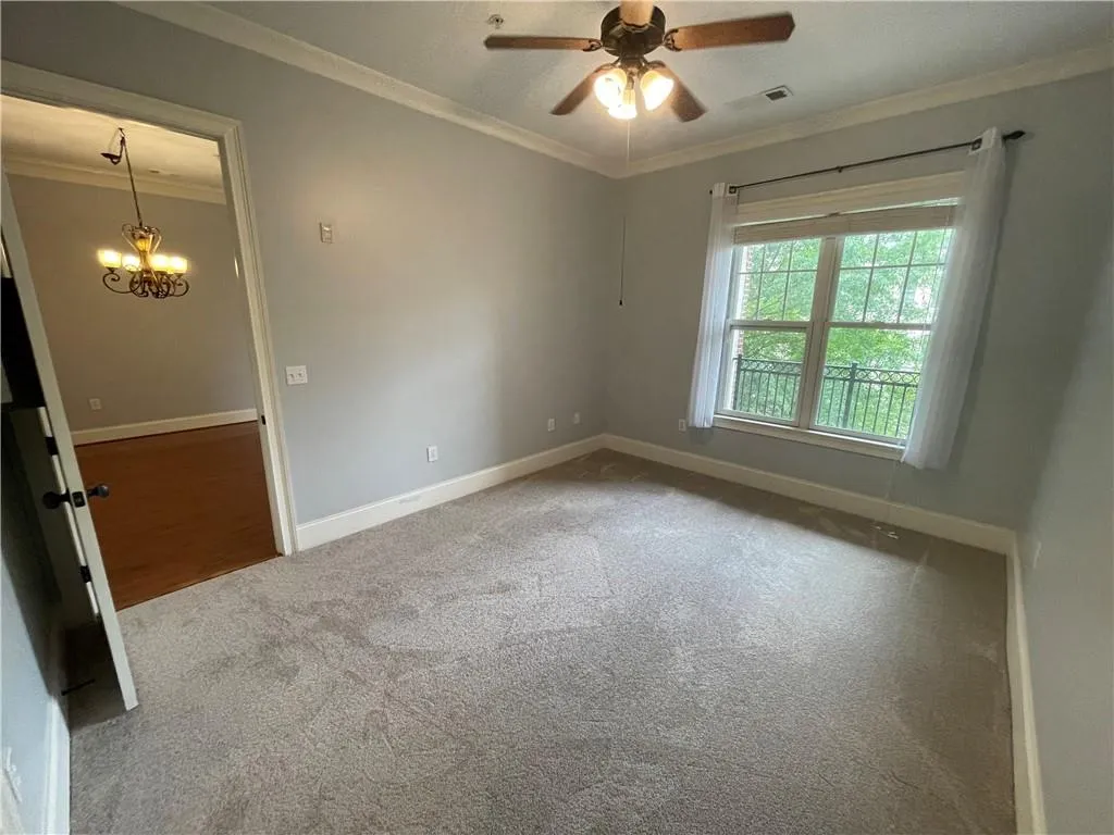 Carpeted spare room featuring ornamental molding, a chandelier, and ceiling fan