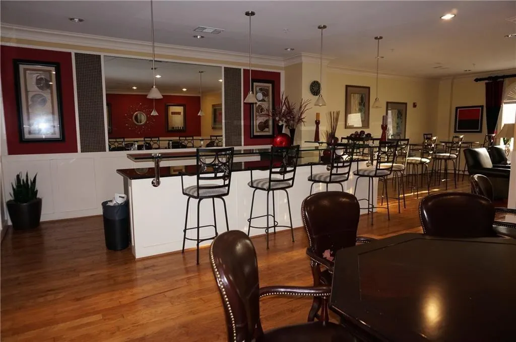 Bar area featuring dark countertops, dark wood-style flooring, crown molding, recessed lighting, and hanging light fixtures