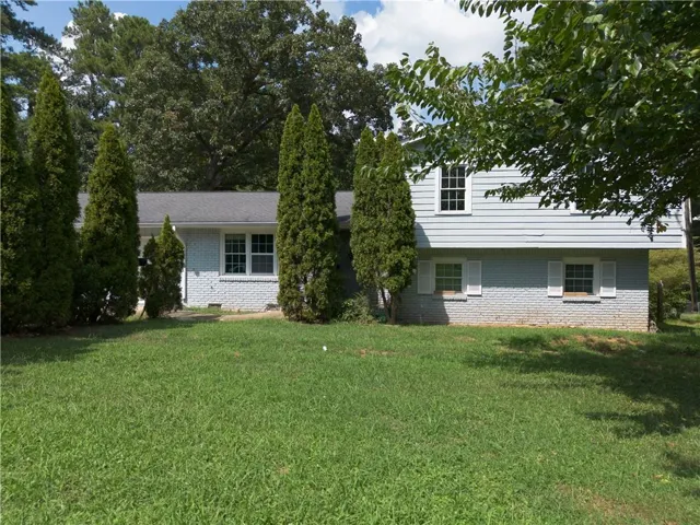 Exterior featuring light blue siding, painted brick foundation, multiple windows with white trim, and a shingled roof
