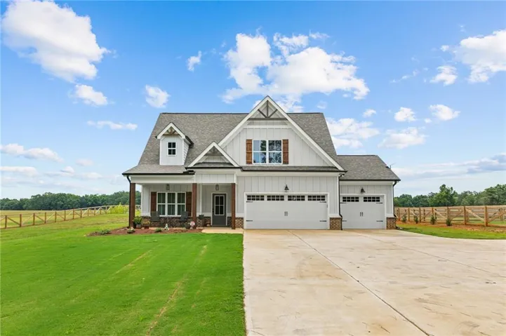 Modern farmhouse exterior featuring white board-and-batten siding, a prominent gable roofline, a three-car garage, and a covered front porch with wood columns