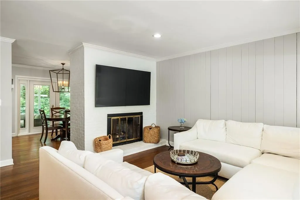 Living room featuring ornamental molding, a brick fireplace, dark hardwood / wood-style floors, and a chandelier