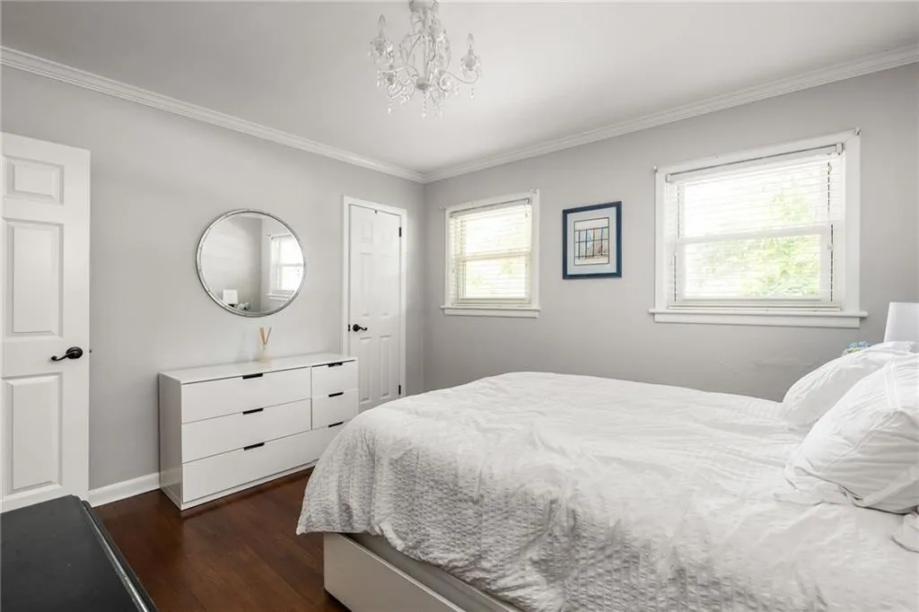 Bedroom with an inviting chandelier, dark hardwood / wood-style flooring, and ornamental molding