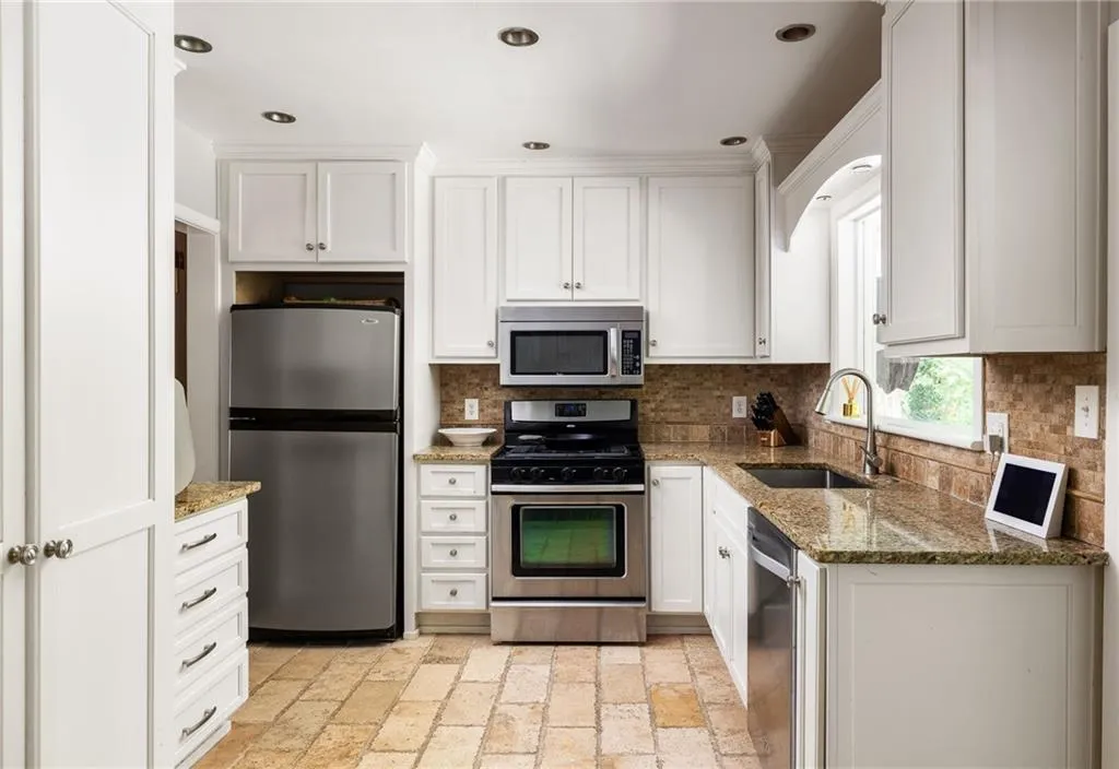 Kitchen featuring white cabinetry, tasteful backsplash, appliances with stainless steel finishes, and sink