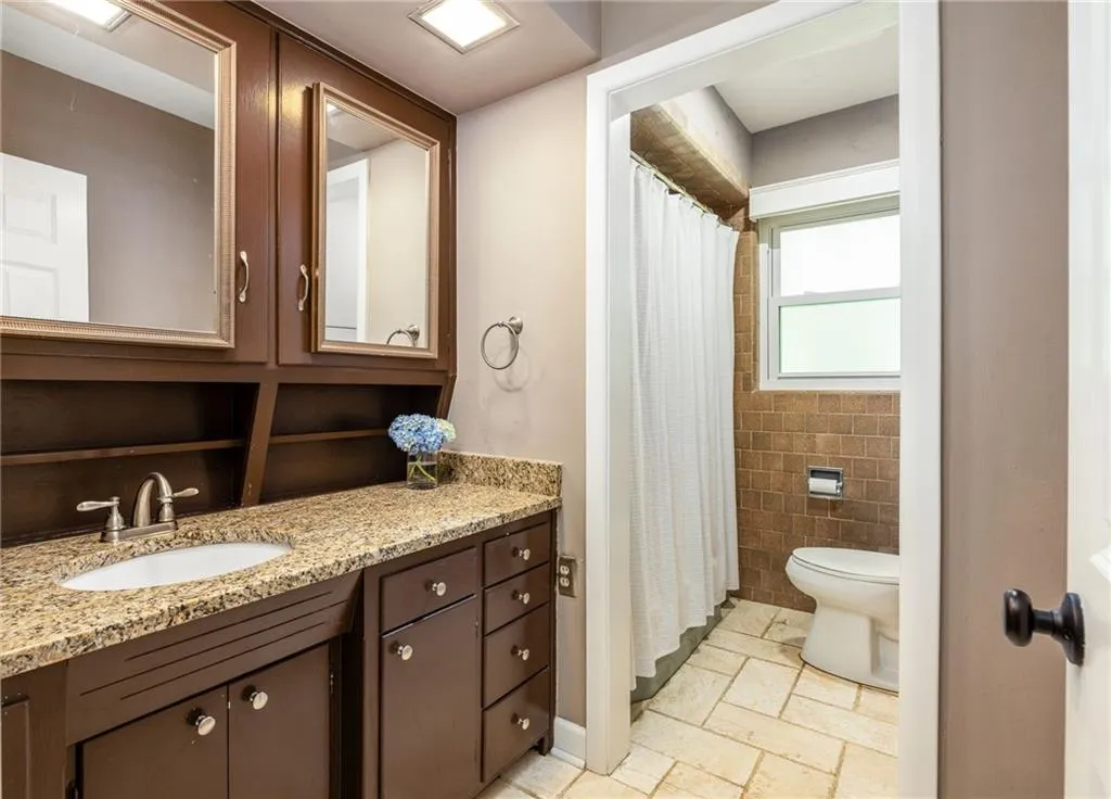 Bathroom featuring tile patterned flooring, tile walls, toilet, and vanity