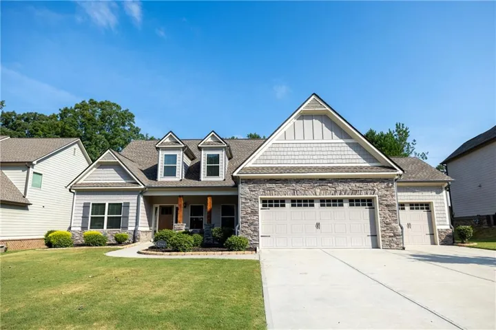 Stone and siding exterior with gabled roof lines, featuring a multi-car garage and dormer windows