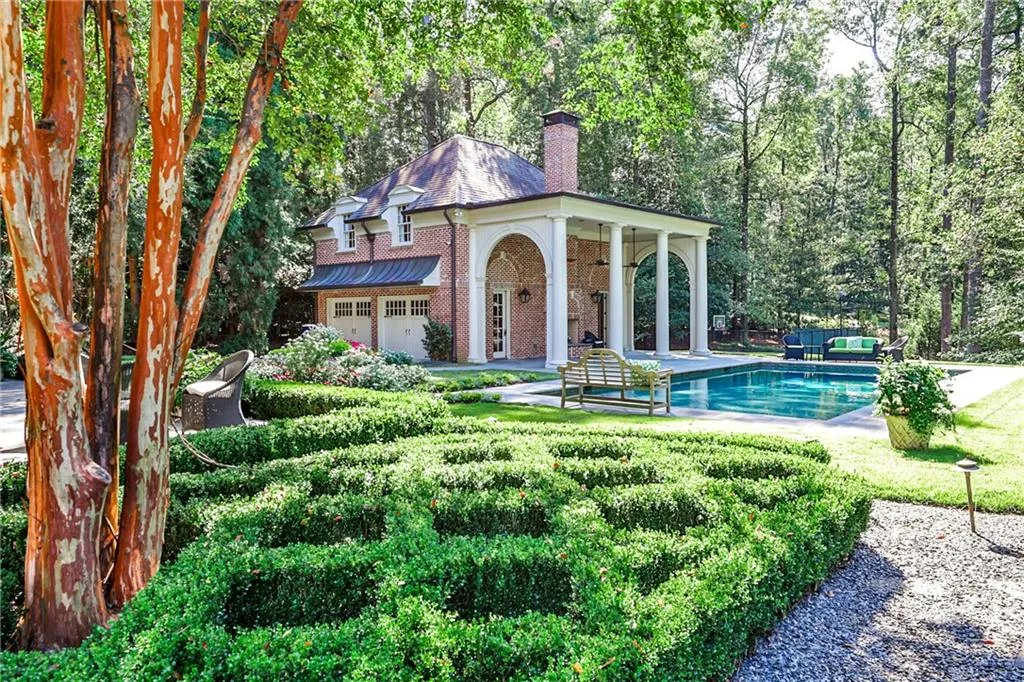 View of front facade with an outdoor pool, brick siding, a patio, a chimney, and ceiling fan