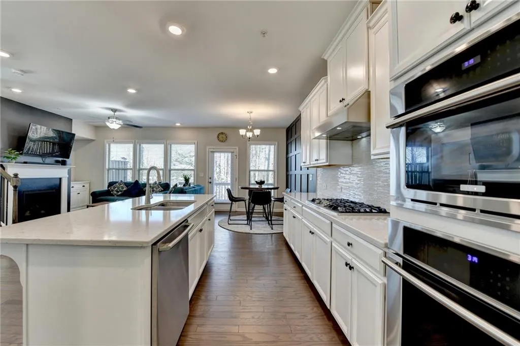 Kitchen featuring stainless steel appliances, a sink, white cabinetry, and under cabinet range hood