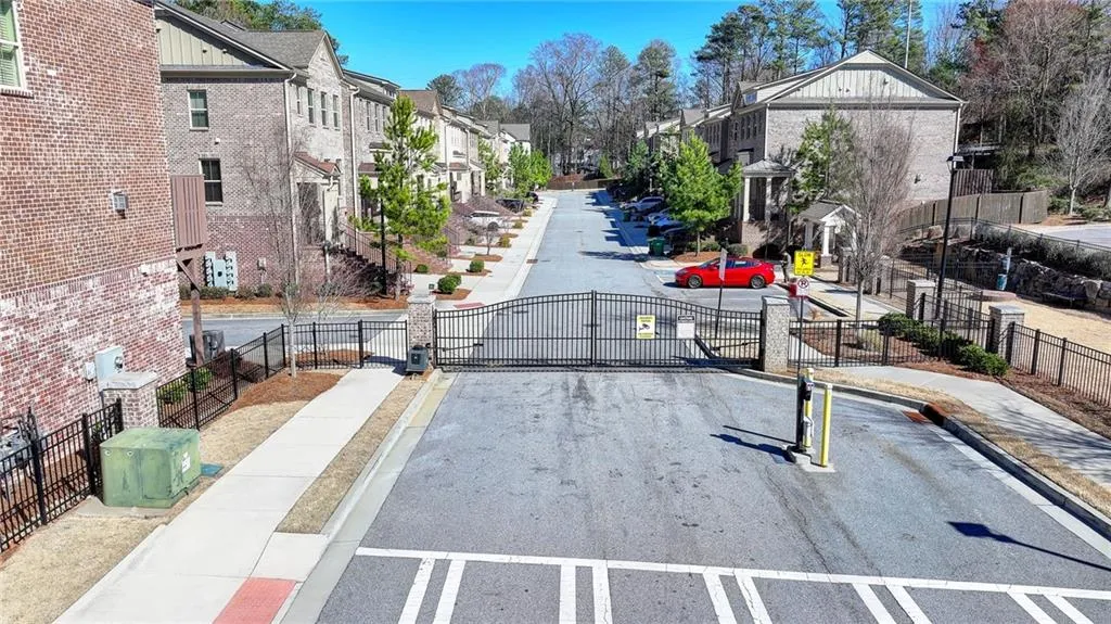 View of road featuring a gate, sidewalks, a gated entry, a residential view, and curbs