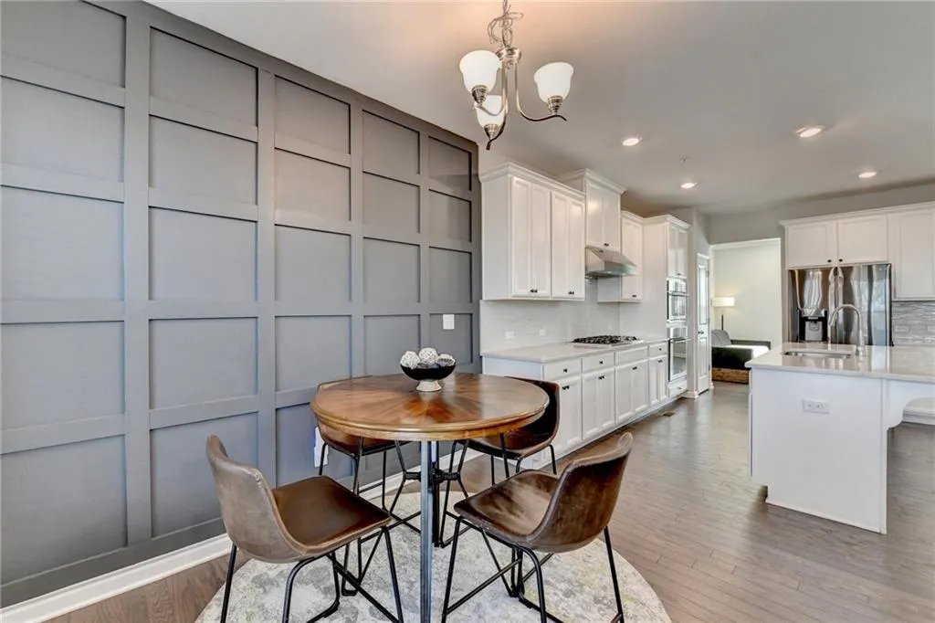 Kitchen with under cabinet range hood, a decorative wall, stainless steel appliances, light countertops, and decorative backsplash