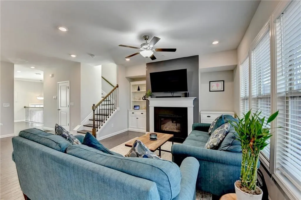 Living area featuring wood finished floors, stairway, a glass covered fireplace, and baseboards