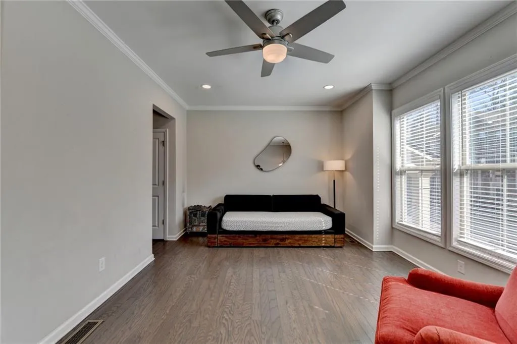 Bedroom featuring ceiling fan, wood finished floors, visible vents, baseboards, and crown molding