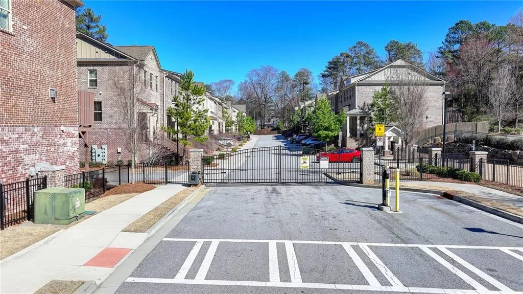 View of road featuring a gated entry, sidewalks, curbs, a gate, and a residential view