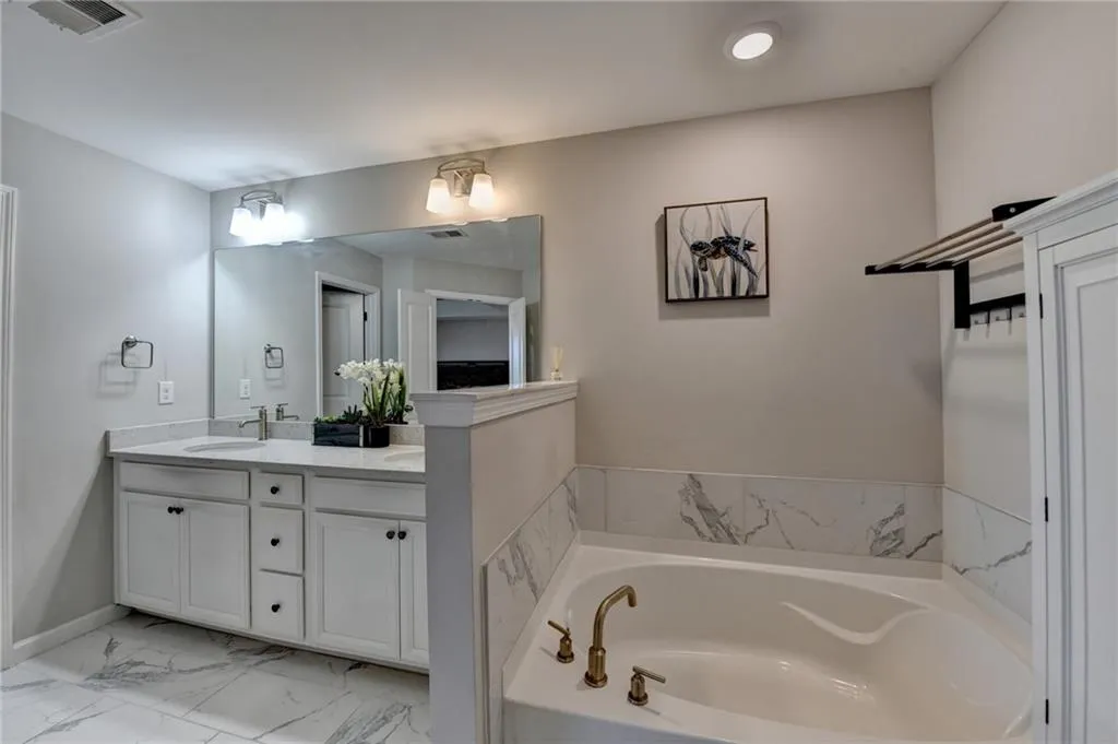 Full bath featuring a bath, marble finish floor, vanity, and visible vents
