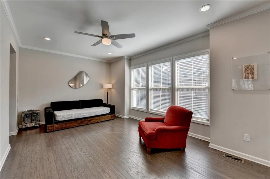 Living area with hardwood / wood-style flooring, recessed lighting, visible vents, baseboards, and crown molding