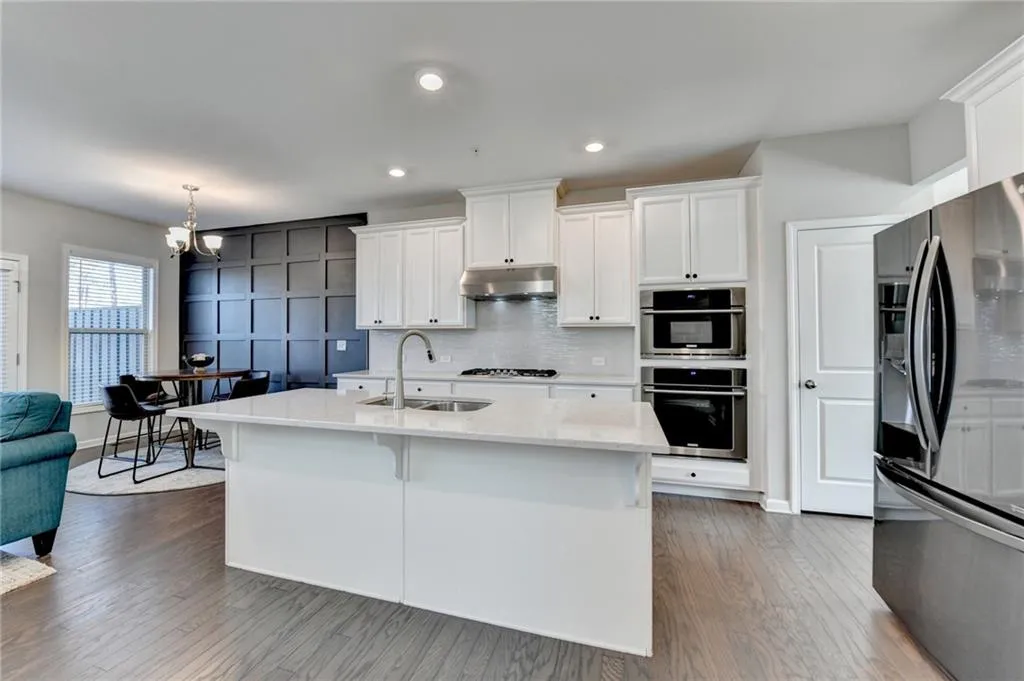 Kitchen with stainless steel appliances, backsplash, white cabinets, a sink, and under cabinet range hood