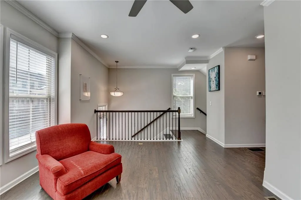Living area with crown molding, dark wood finished floors, an upstairs landing, and baseboards