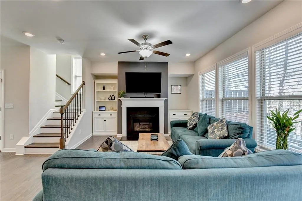 Living room featuring baseboards, a fireplace with flush hearth, stairway, and wood finished floors