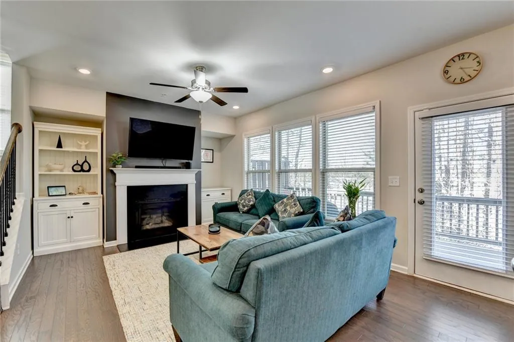 Living room featuring dark wood-style flooring, a glass covered fireplace, a ceiling fan, and recessed lighting