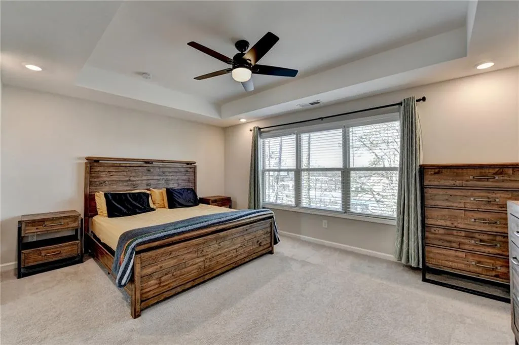 Bedroom with a tray ceiling, recessed lighting, light colored carpet, visible vents, and baseboards