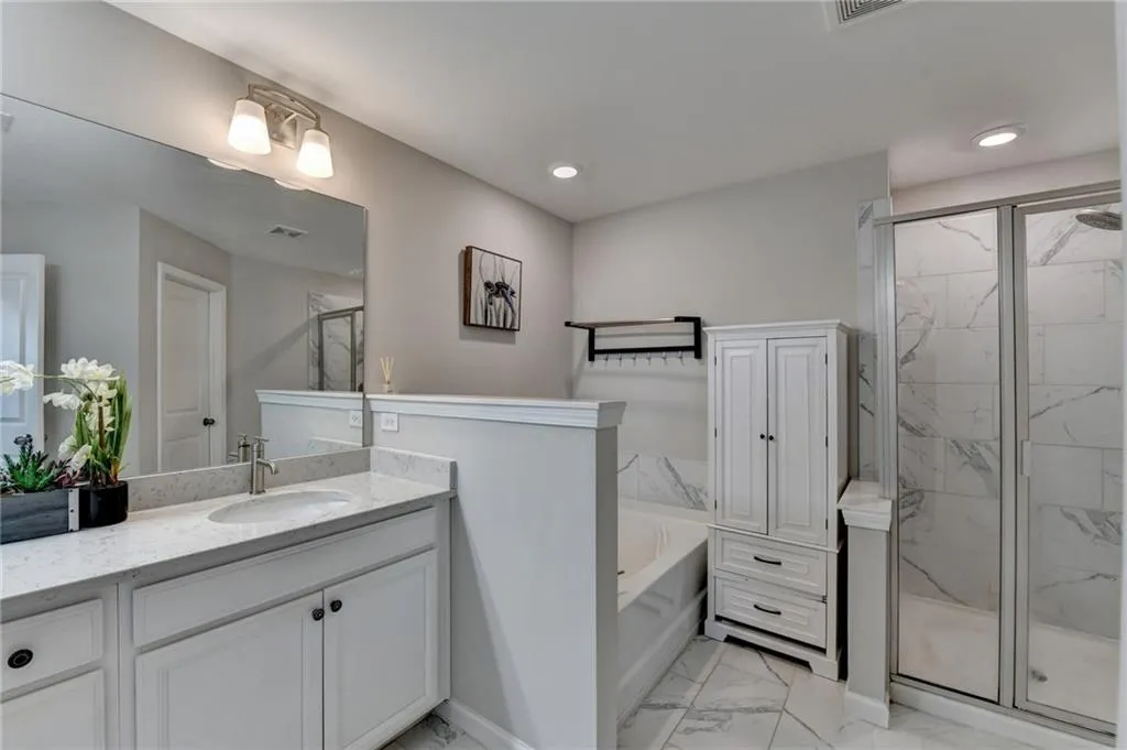 Full bathroom with a garden tub, visible vents, vanity, marble finish floor, and a marble finish shower