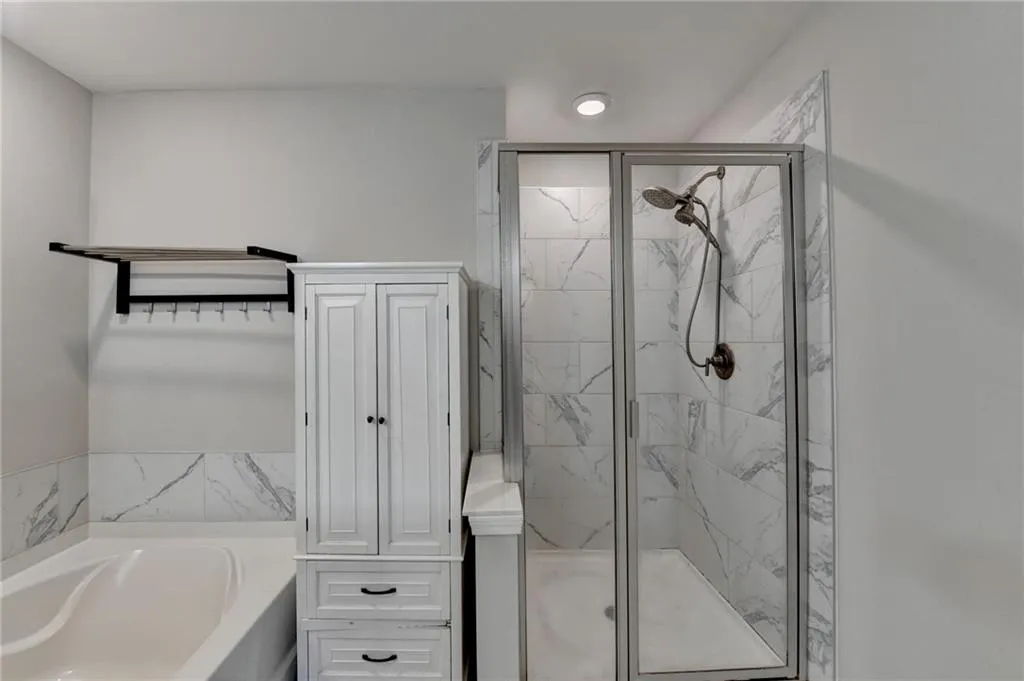 Full bathroom featuring a marble finish shower and a bath
