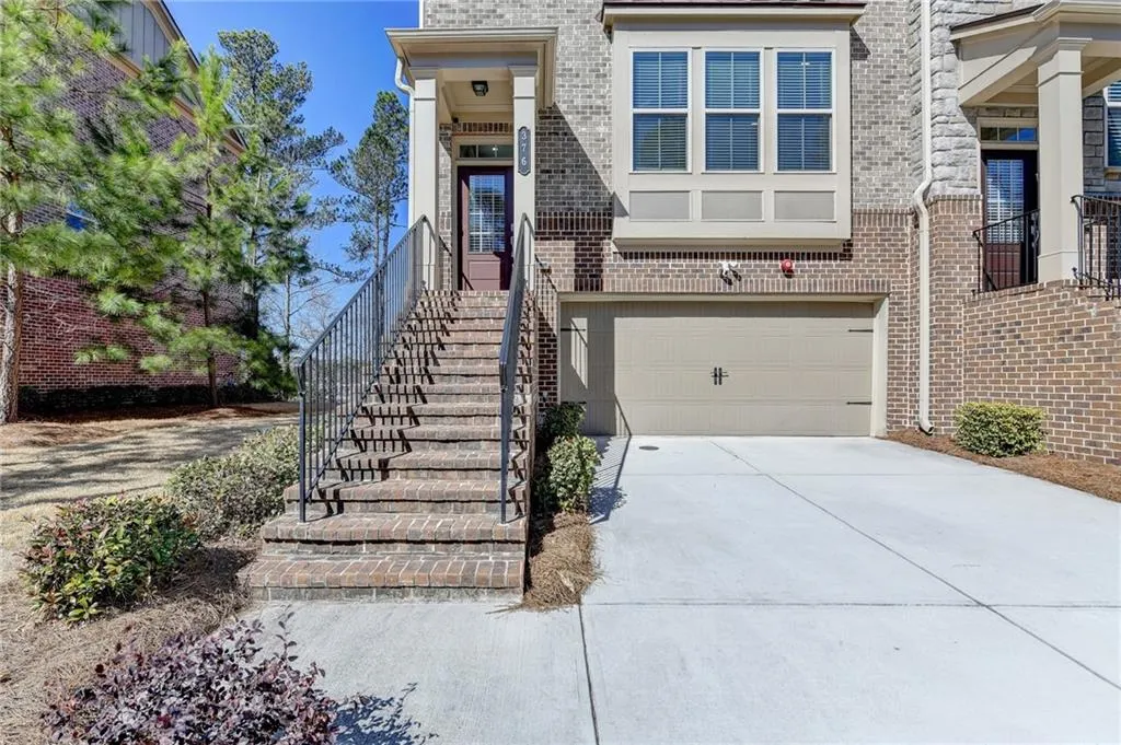 Property entrance featuring a garage, driveway, and brick siding