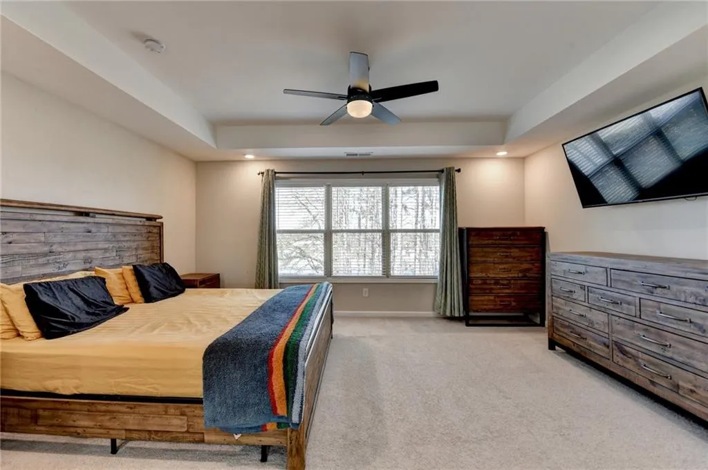 Bedroom with recessed lighting, light colored carpet, a ceiling fan, baseboards, and a raised ceiling