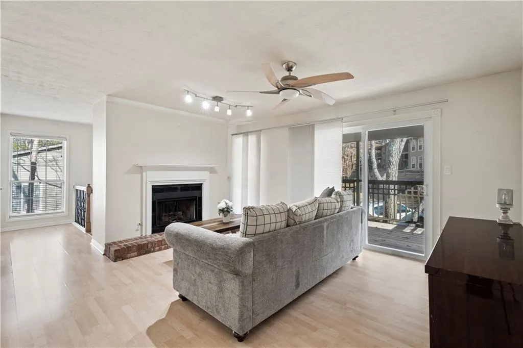 Living room with ceiling fan, light wood-style floors, a brick fireplace, and a textured ceiling Living room with ceiling fan, light wood-style floors, a brick fireplace, and a textured ceiling