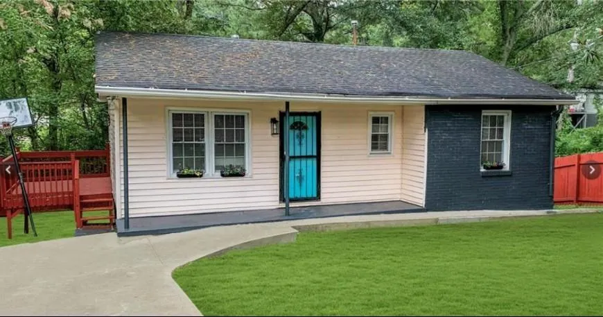 Modern cottage-style residence featuring a striking turquoise entry door, crisp white horizontal siding, and a charcoal-gray accent section