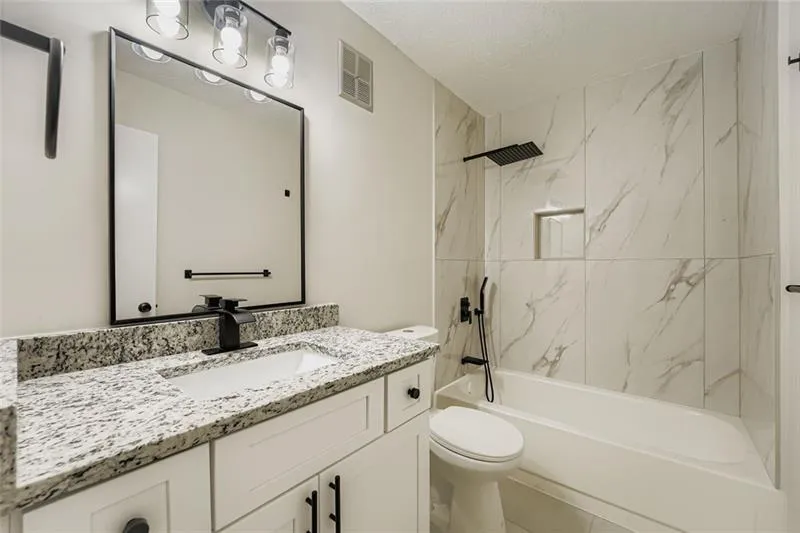 Bathroom with bathing tub / shower combination, vanity, and a textured ceiling