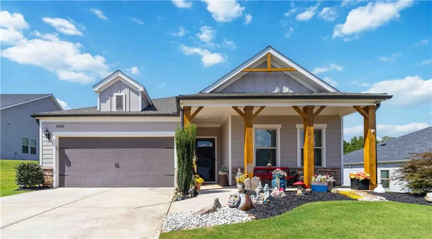 Light gray siding exterior with stone accents, covered front porch with exposed timber posts, attached garage, concrete driveway, and manicured landscaping