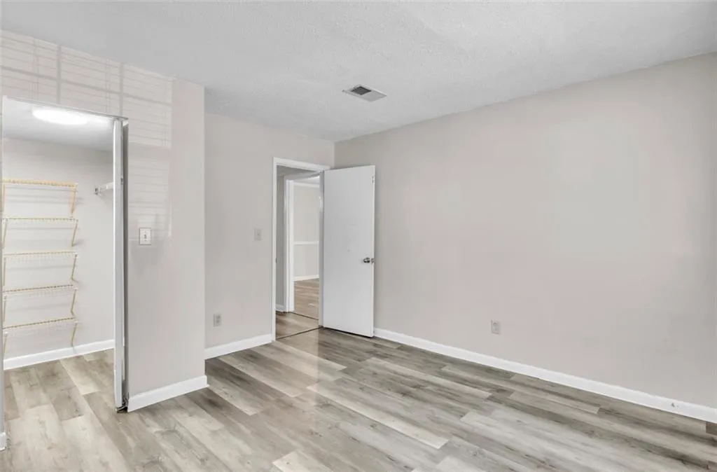 Unfurnished bedroom featuring a walk in closet, a textured ceiling, and light wood finished floors