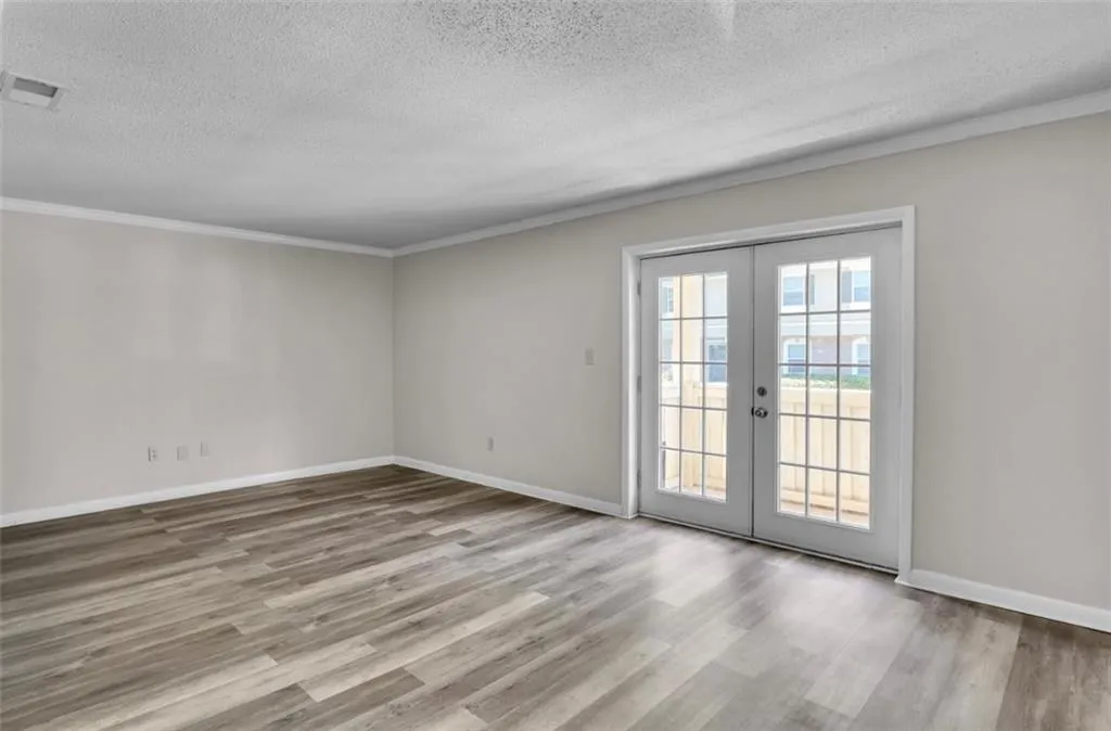 Spare room with french doors, crown molding, a textured ceiling, and light wood-style flooring