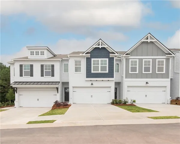 Modern townhome exteriors featuring white brick, gray siding, and dark blue shingle accents