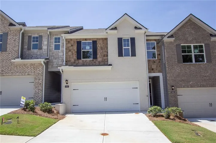 Contemporary brick and stone exterior featuring a two-story facade with mixed material cladding, gabled rooflines, and multiple multi-pane windows