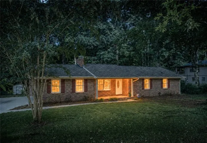 Welcoming brick ranch home illuminated by multiple windows across the front facade