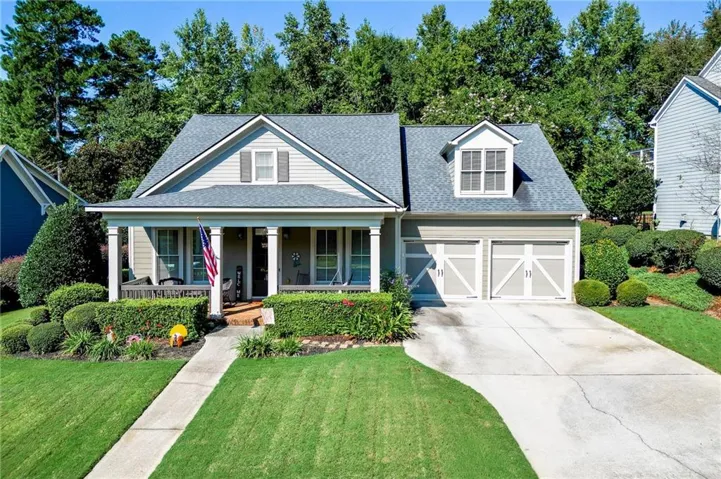 Craftsman-style home featuring a covered front porch, dormer window, two-car garage with carriage-style doors, and established landscaping