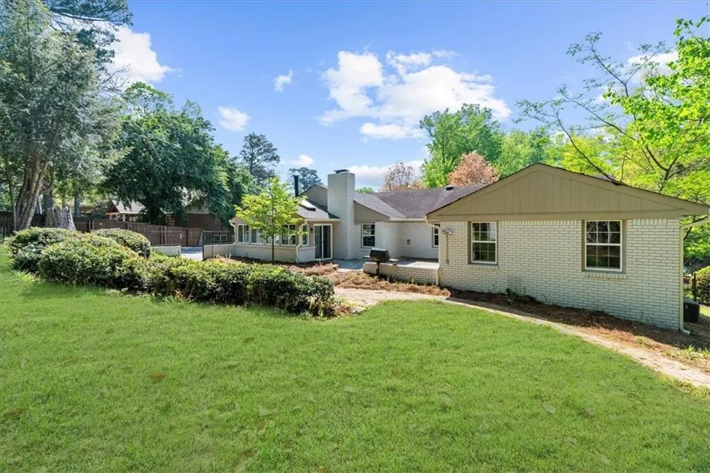 Back of property featuring a lawn, a chimney, and brick siding